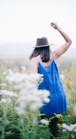 woman in blue spaghetti strap with black pants walking on the field on flowers in daytime \ thumbnail