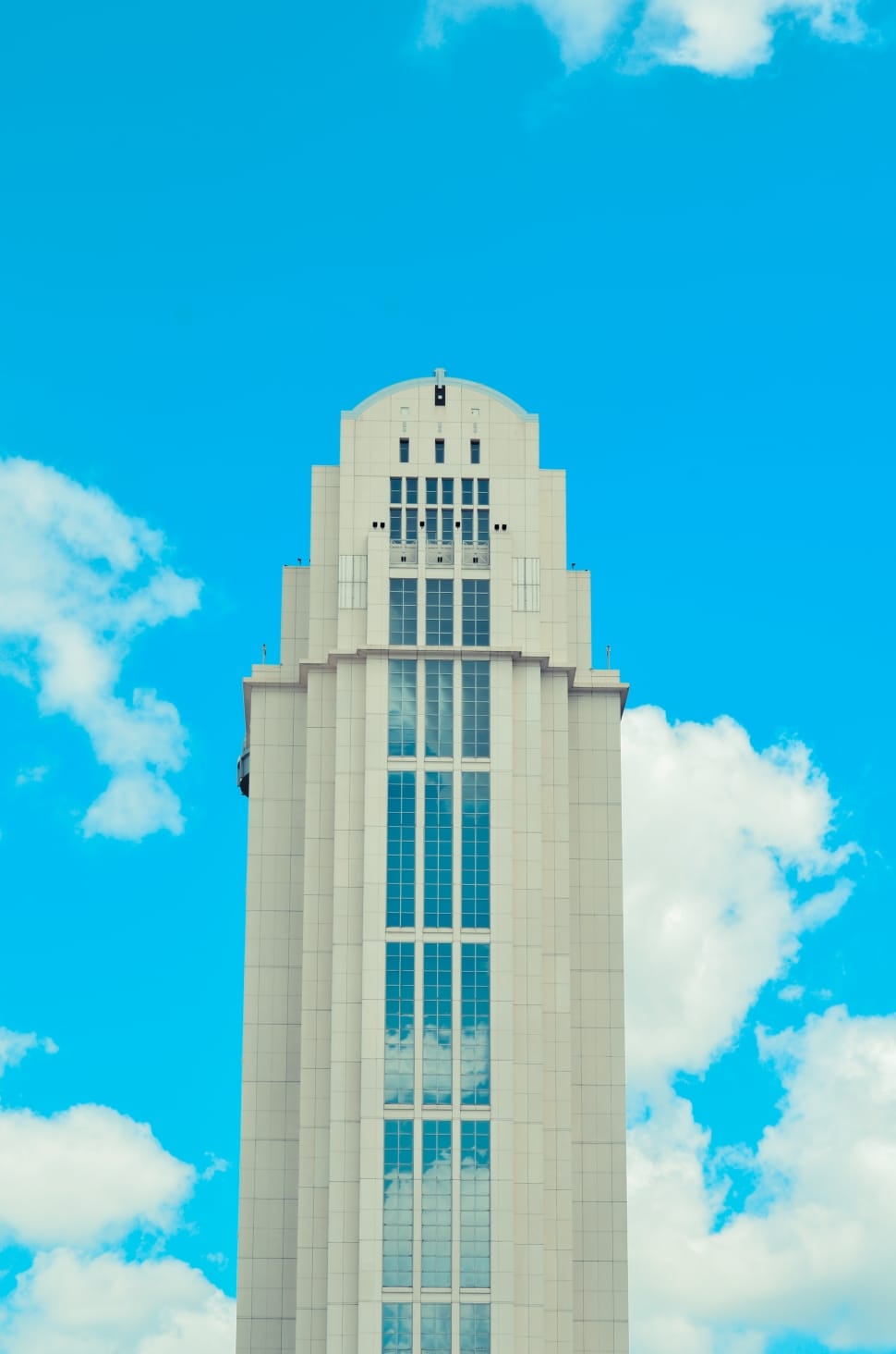 low angle view photo of white high-rise building under blue sky with cumulus clouds preview