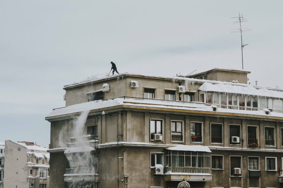 man on top of building removing the snow preview