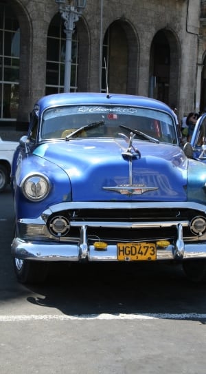 blue classic car near grey concrete building at daytime thumbnail