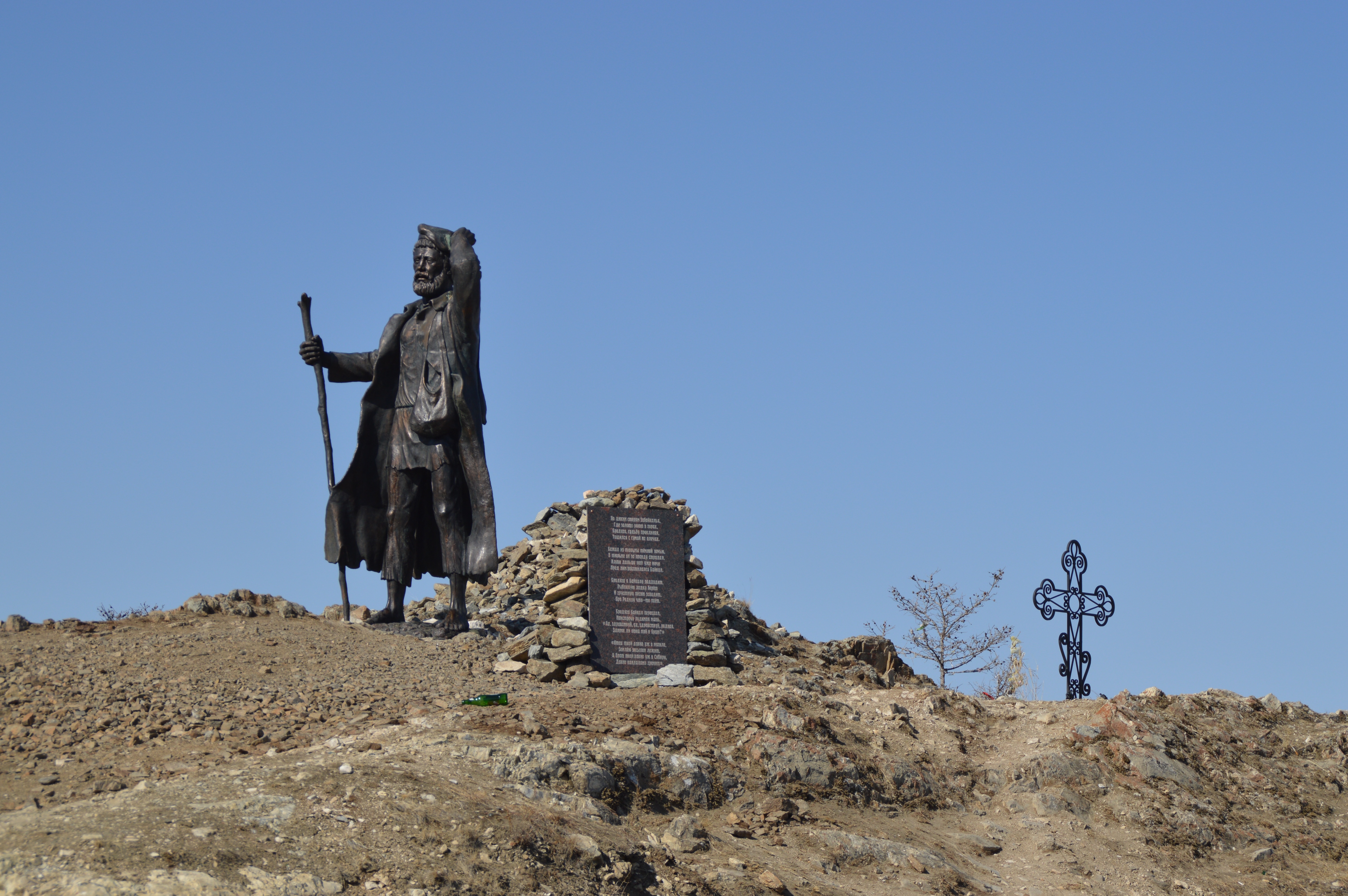 moses statue on brown dirt and cross statue at distance during daytime