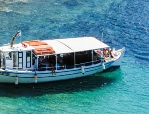 white and blue ferry boat on blue and green body of water during daytime thumbnail