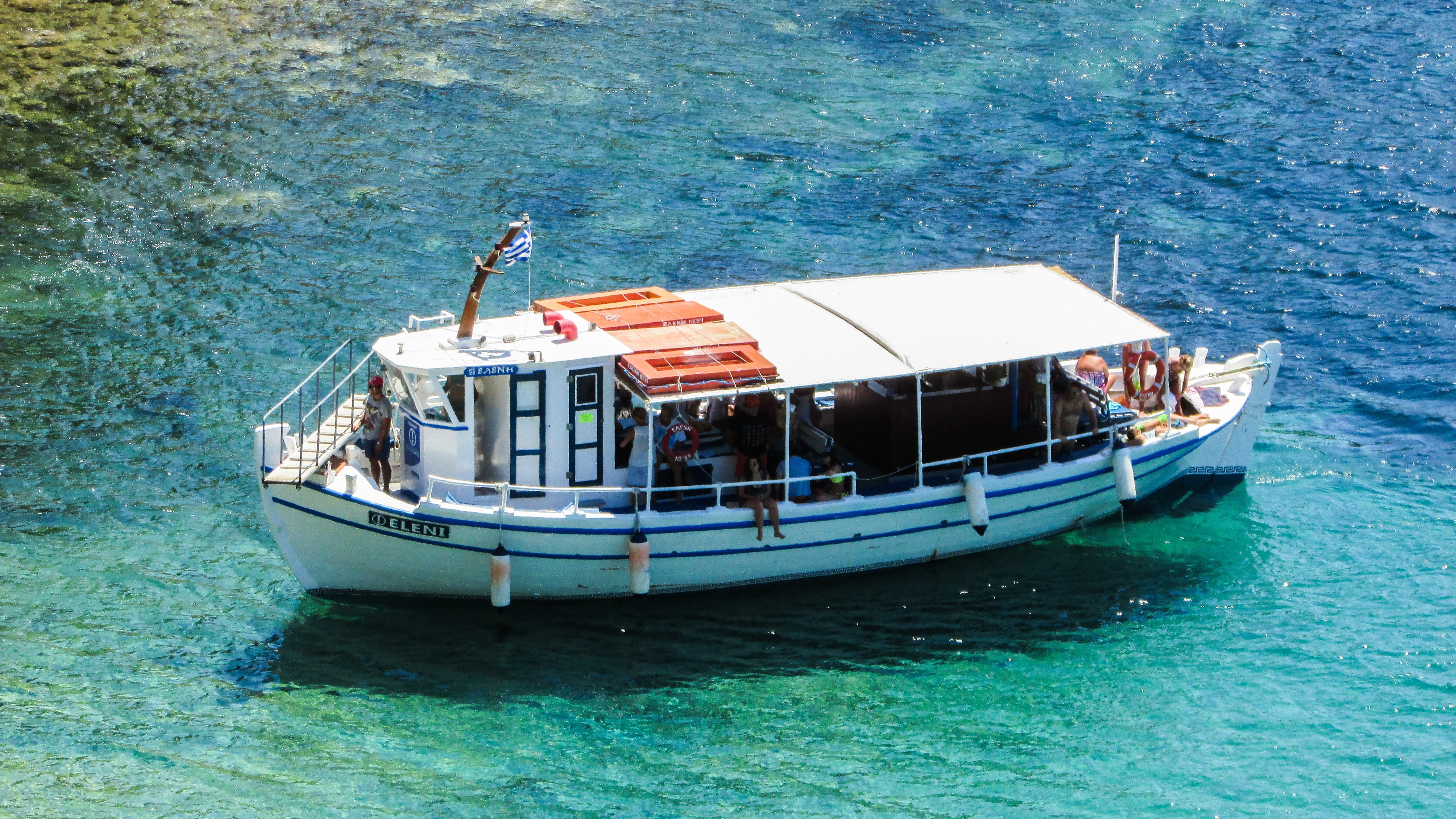 white and blue ferry boat on blue and green body of water during daytime