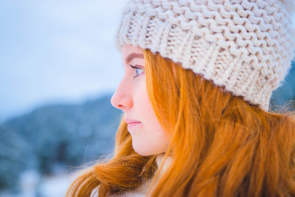 close photo of woman with orange hair wearing white knit cap preview
