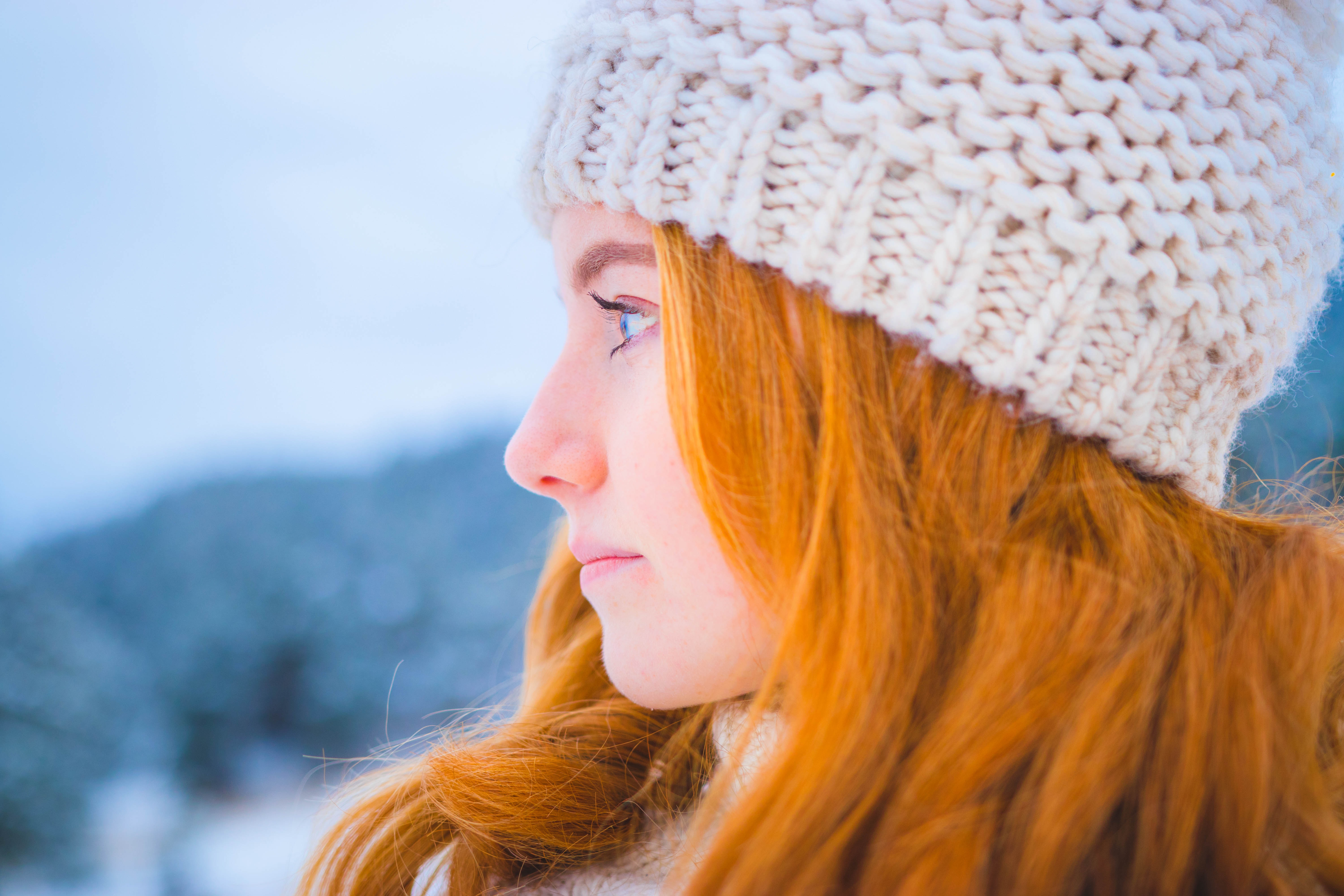 close photo of woman with orange hair wearing white knit cap