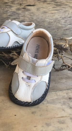toddler's white-and-gray shoes on brown wooden board thumbnail