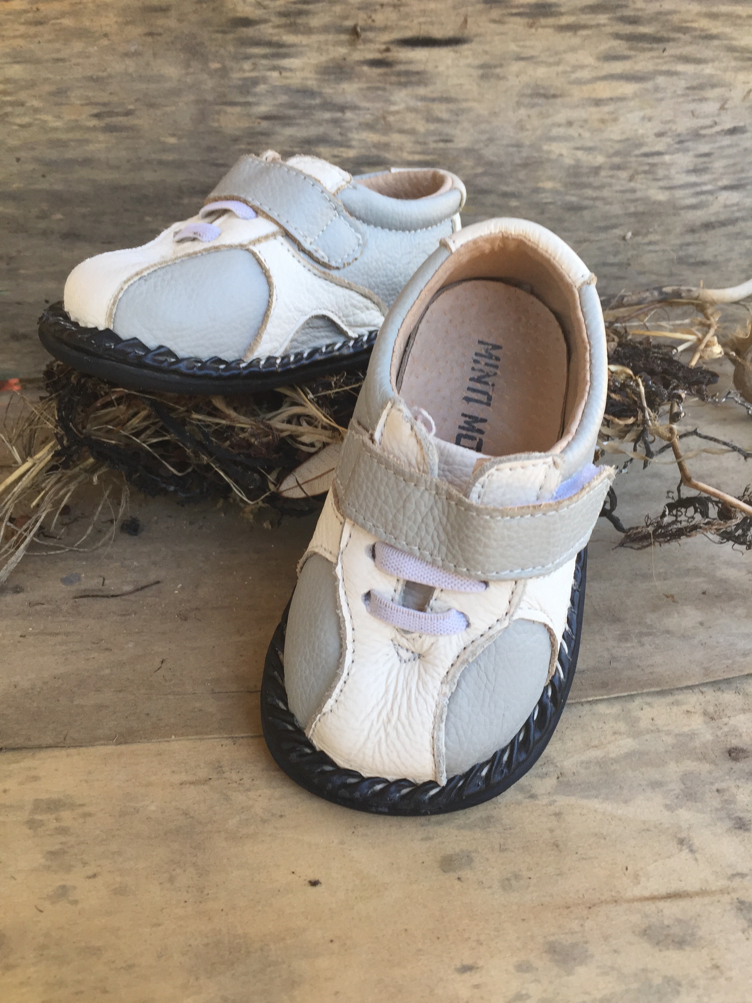 toddler's white-and-gray shoes on brown wooden board