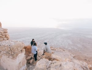 three person's on the beige rock formation during daytime thumbnail