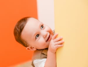 boy's grey and white shirt behind orange wall paint inside the room thumbnail