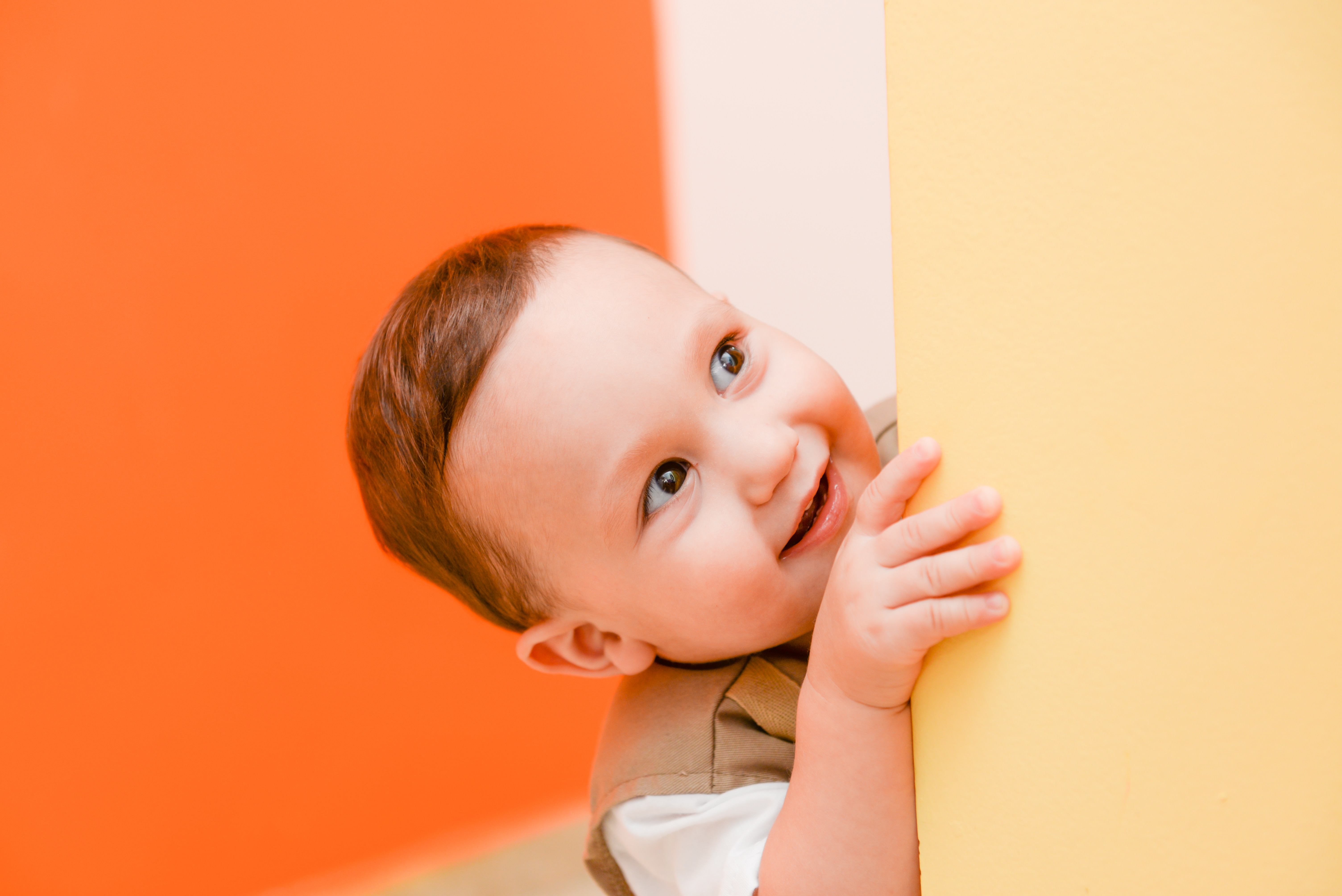 boy's grey and white shirt behind orange wall paint inside the room