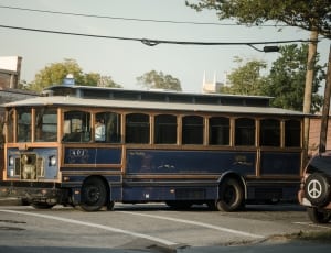 blue and brown bus on gray road during daytime thumbnail