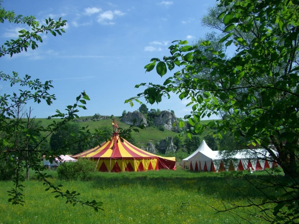 red and yellow circus tent beside white tent outside during daytime preview
