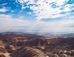 landscape photo of brown mountains under cloudy blue sky during daytime thumbnail