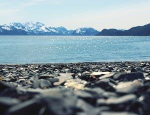 close photo of seashore near body of water and mountains thumbnail
