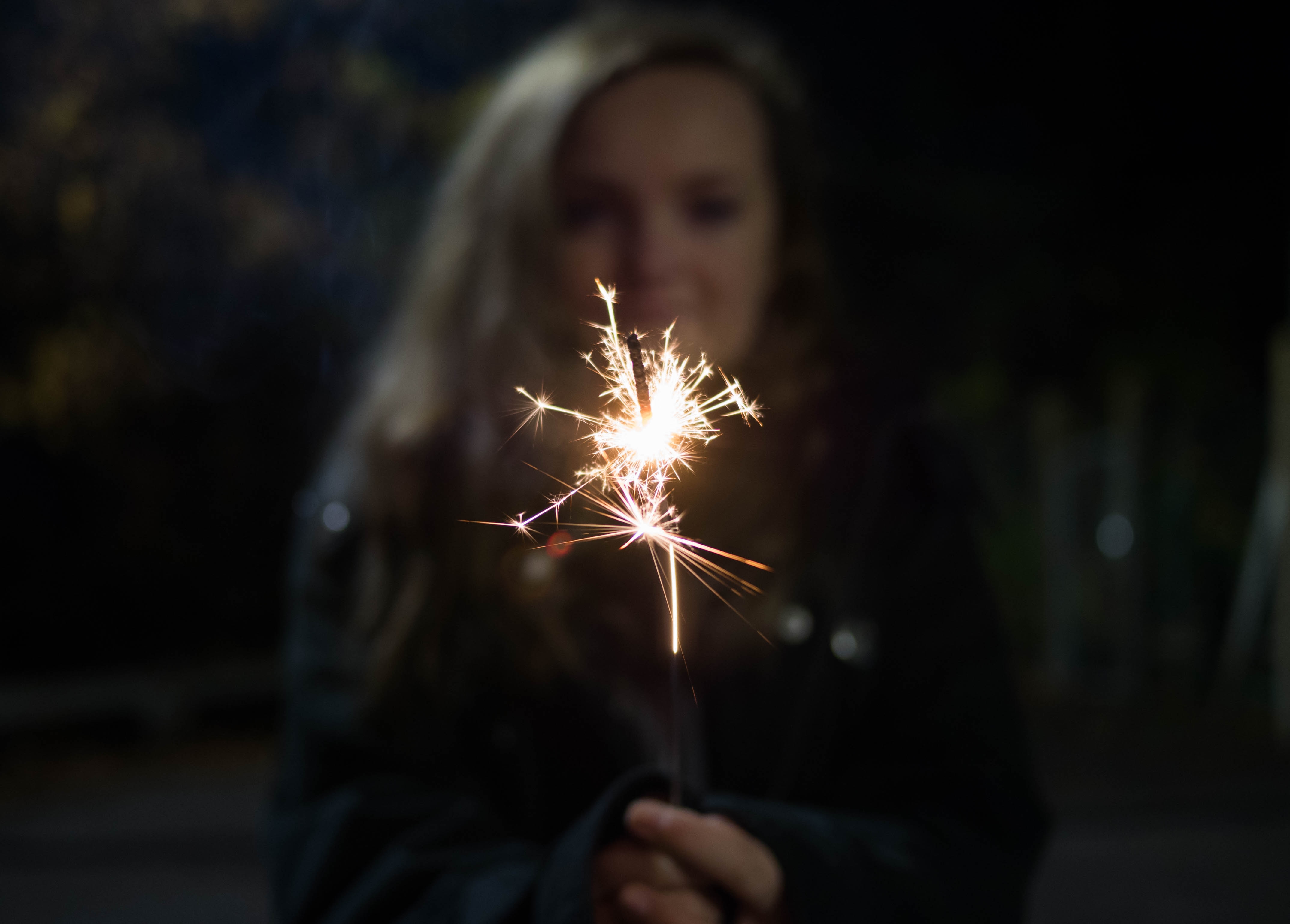 woman in black jacket  holding sparkler
