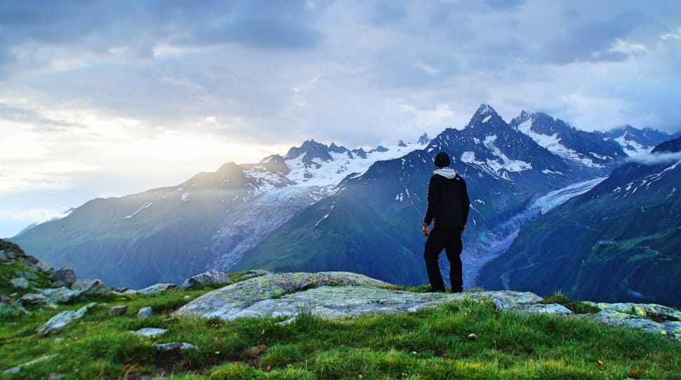 man in black jacket standing watching mountains preview