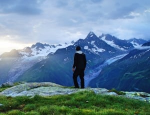 man in black jacket standing watching mountains thumbnail