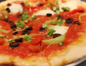 pizza with black olives and parsley leaves on top thumbnail