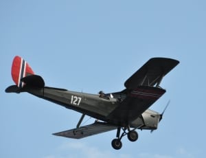 brown 127 plane flying during daytime under blue sky with white thin clouds thumbnail