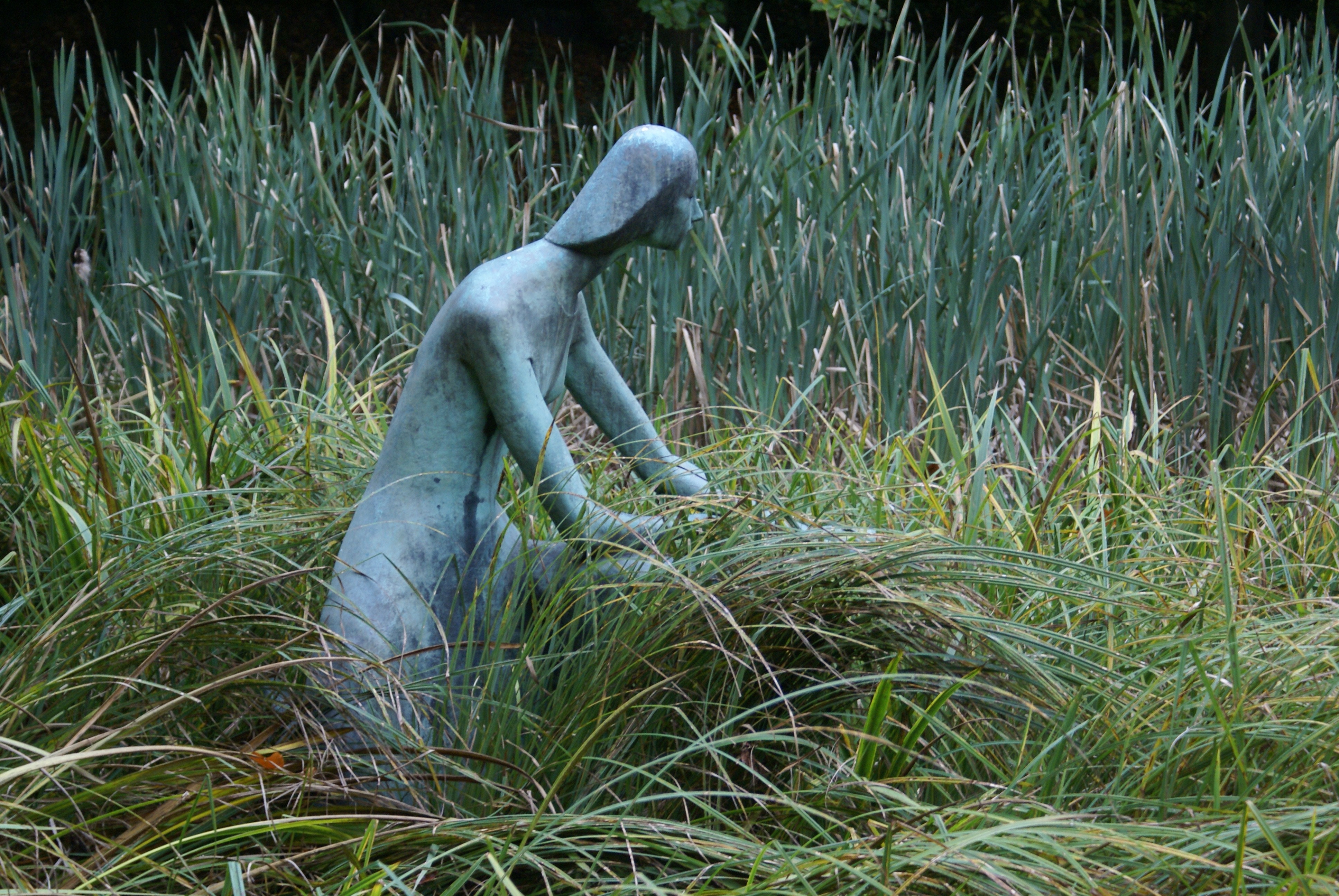 grey woman statue on green grass field during daytime