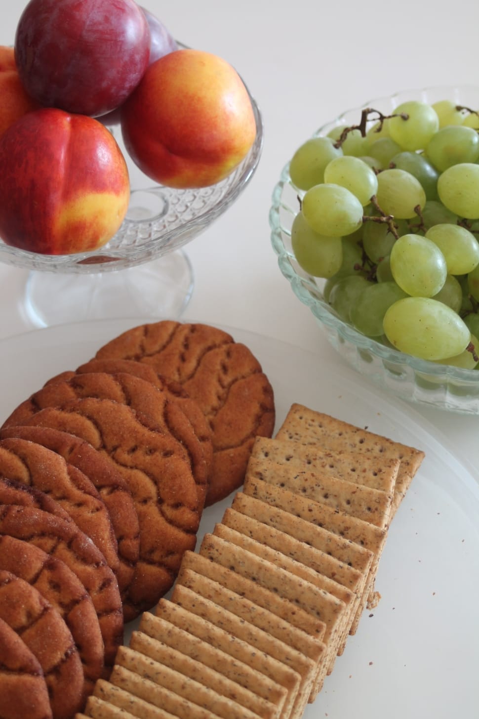 cookies and crackers on plate and red apple and green grape fruit preview