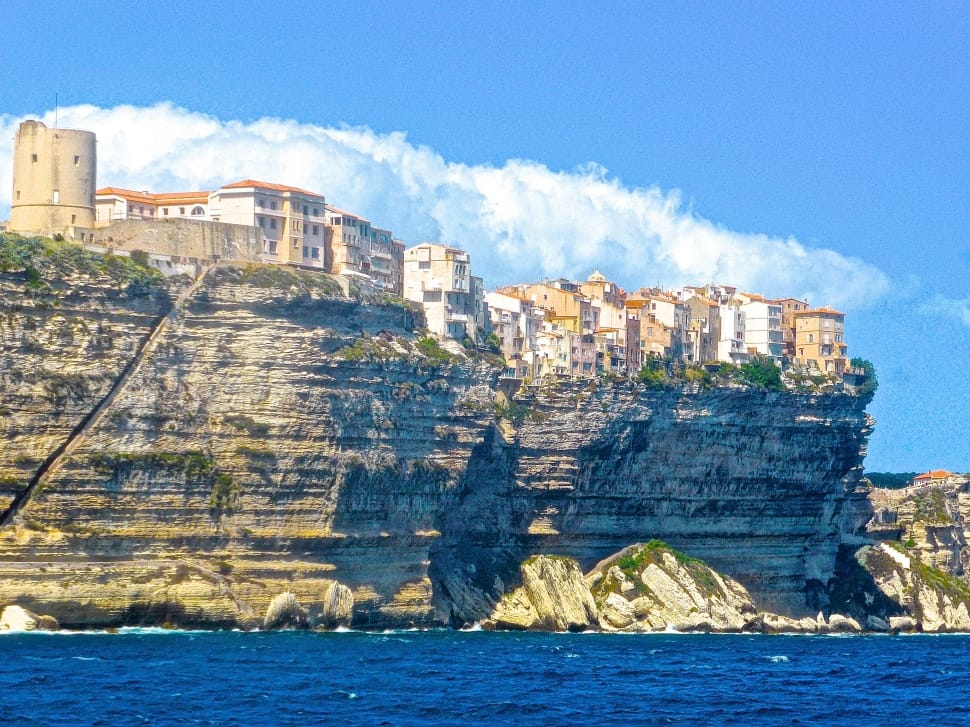 white and beige buildings on gray high cliff during daytime preview