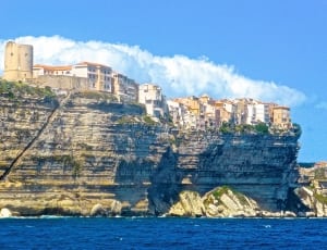 white and beige buildings on gray high cliff during daytime thumbnail