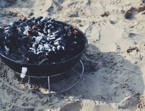 black charcoal grill with charcoal on sand thumbnail