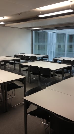 room with white tables and black chairs thumbnail