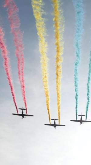 three airplanes discharging red yellow and blue smokes in air during daytime thumbnail