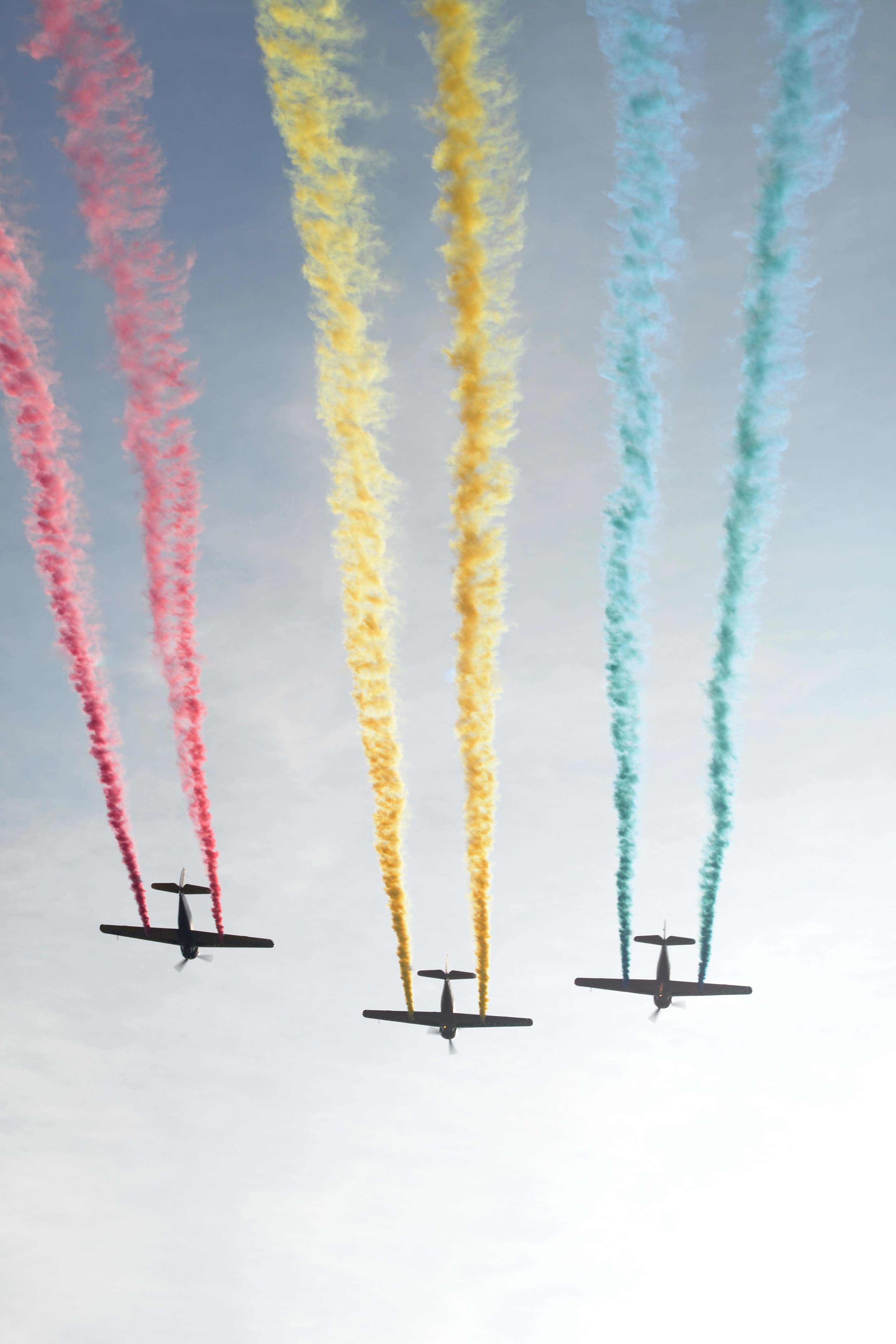 three airplanes discharging red yellow and blue smokes in air during daytime