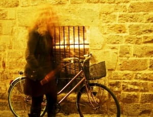 woman with bicycle next to concrete wall thumbnail