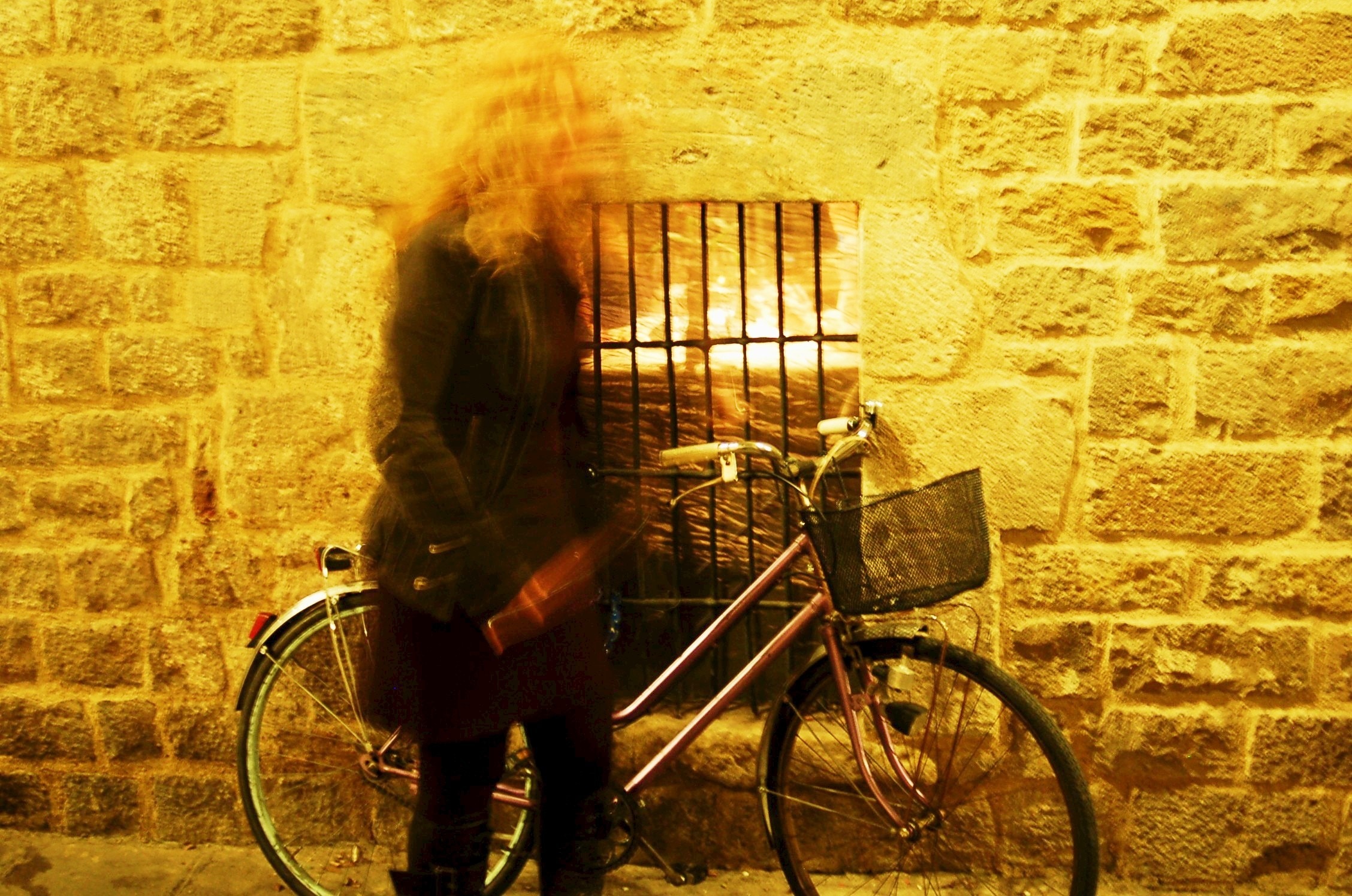 woman with bicycle next to concrete wall