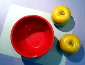 two green apple fruits near round red bowl thumbnail