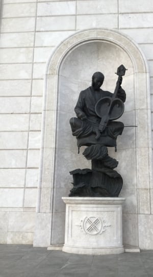 man using string instrument concrete statue thumbnail