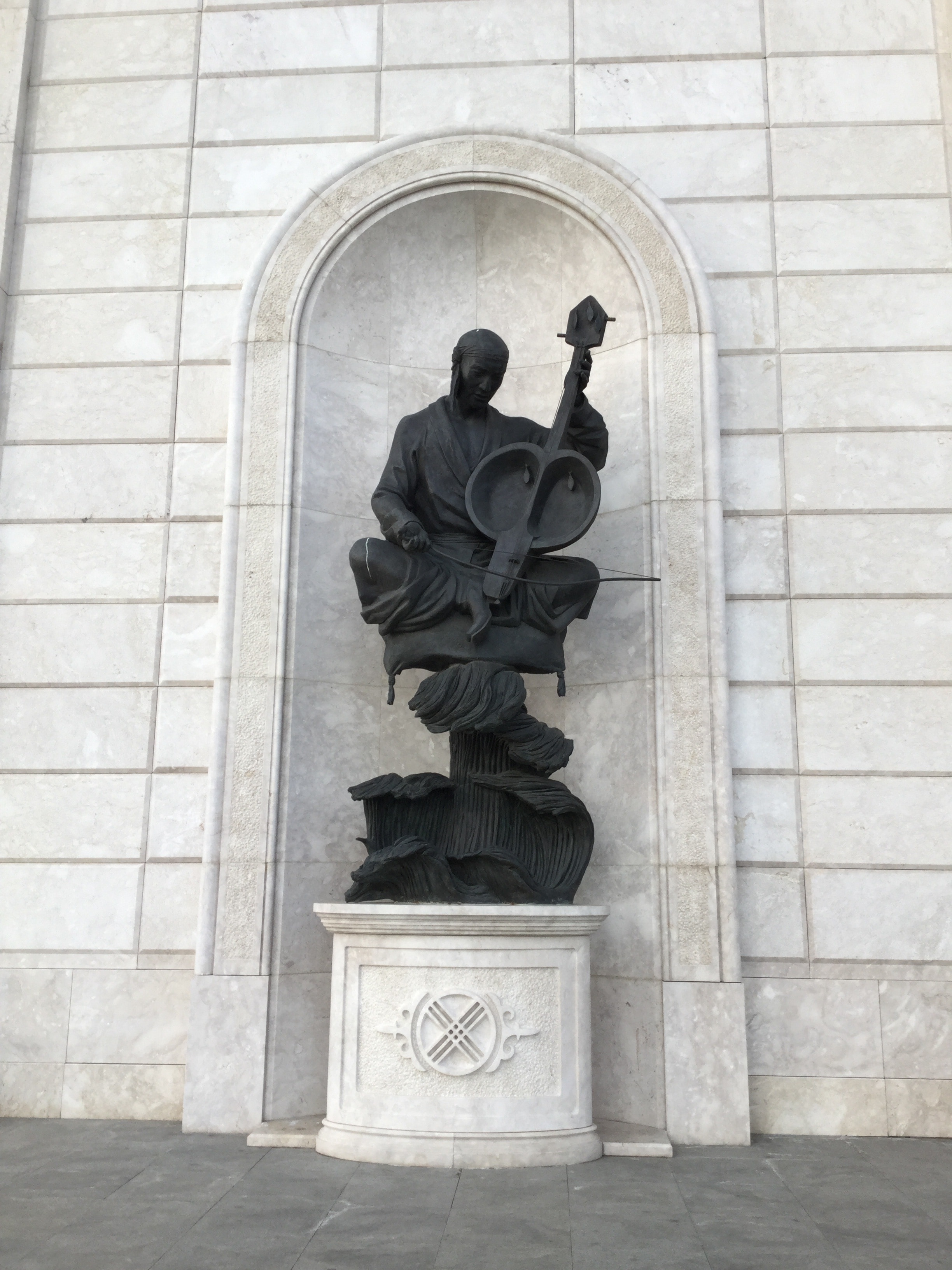 man using string instrument concrete statue
