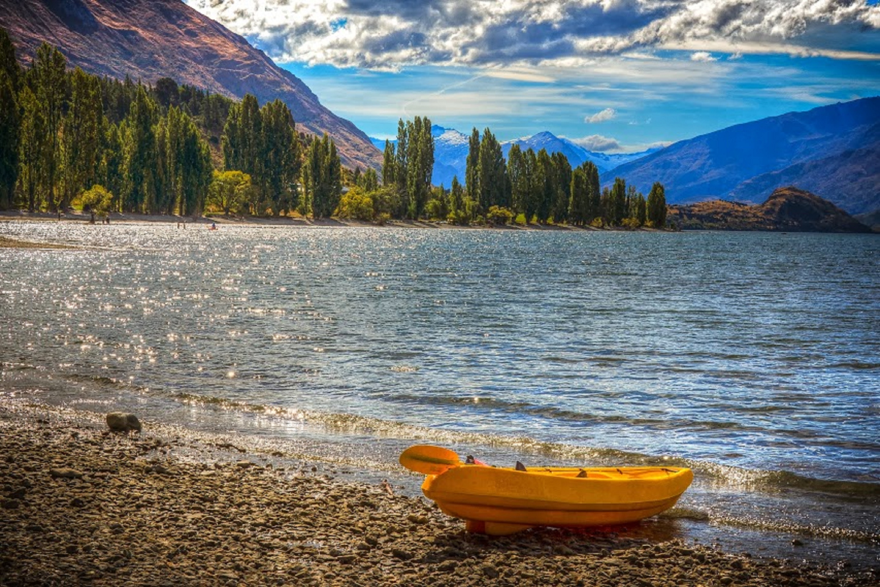 yellow kayak near body of water under blue sky during day time