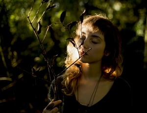 woman wearing black scoop neck top holding tree branch thumbnail