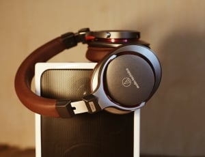 brown and gray wireless headphones on white speaker thumbnail