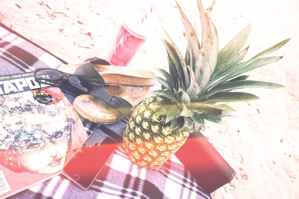 pineapple beside iphone 6 and sandals on top of white and black textile preview