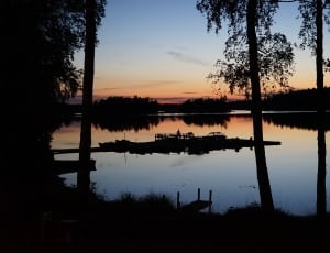 silhouette of trees on lake during nighttime thumbnail