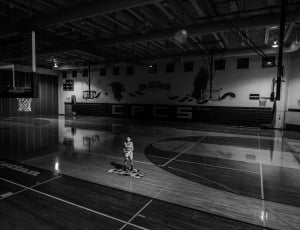grayscale photograph of a man standing in the middle of the basketball court thumbnail