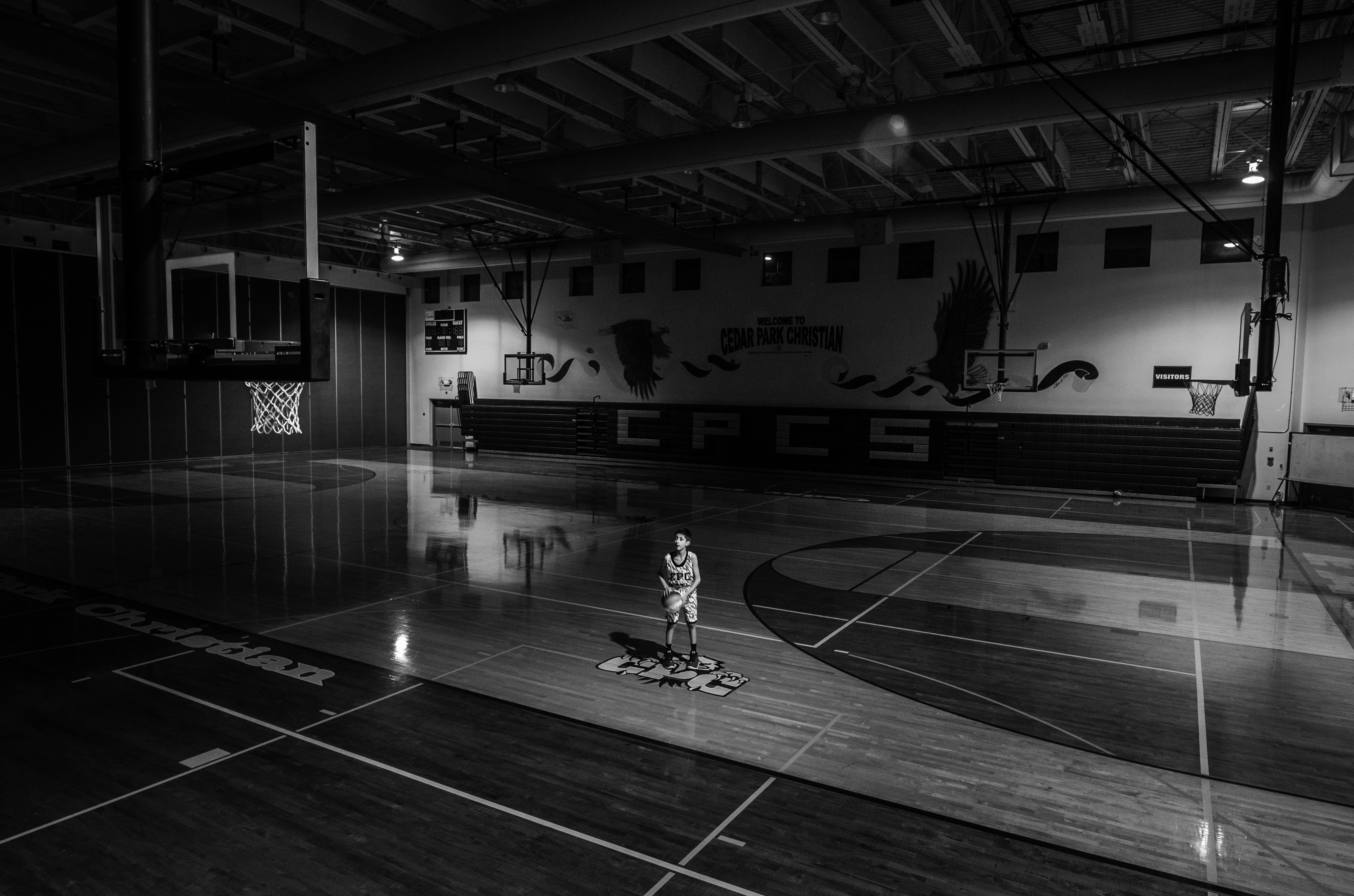 grayscale photograph of a man standing in the middle of the basketball court