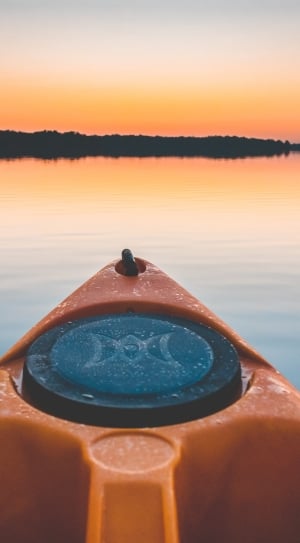 close up photo of a black and yellow kayak in lake near island during sunset thumbnail