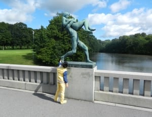 man in yellow suit holding a blue statue during daytime thumbnail