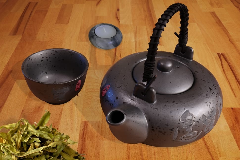 gray steel kettle beside gray steel cup on top of brown wooden surface preview