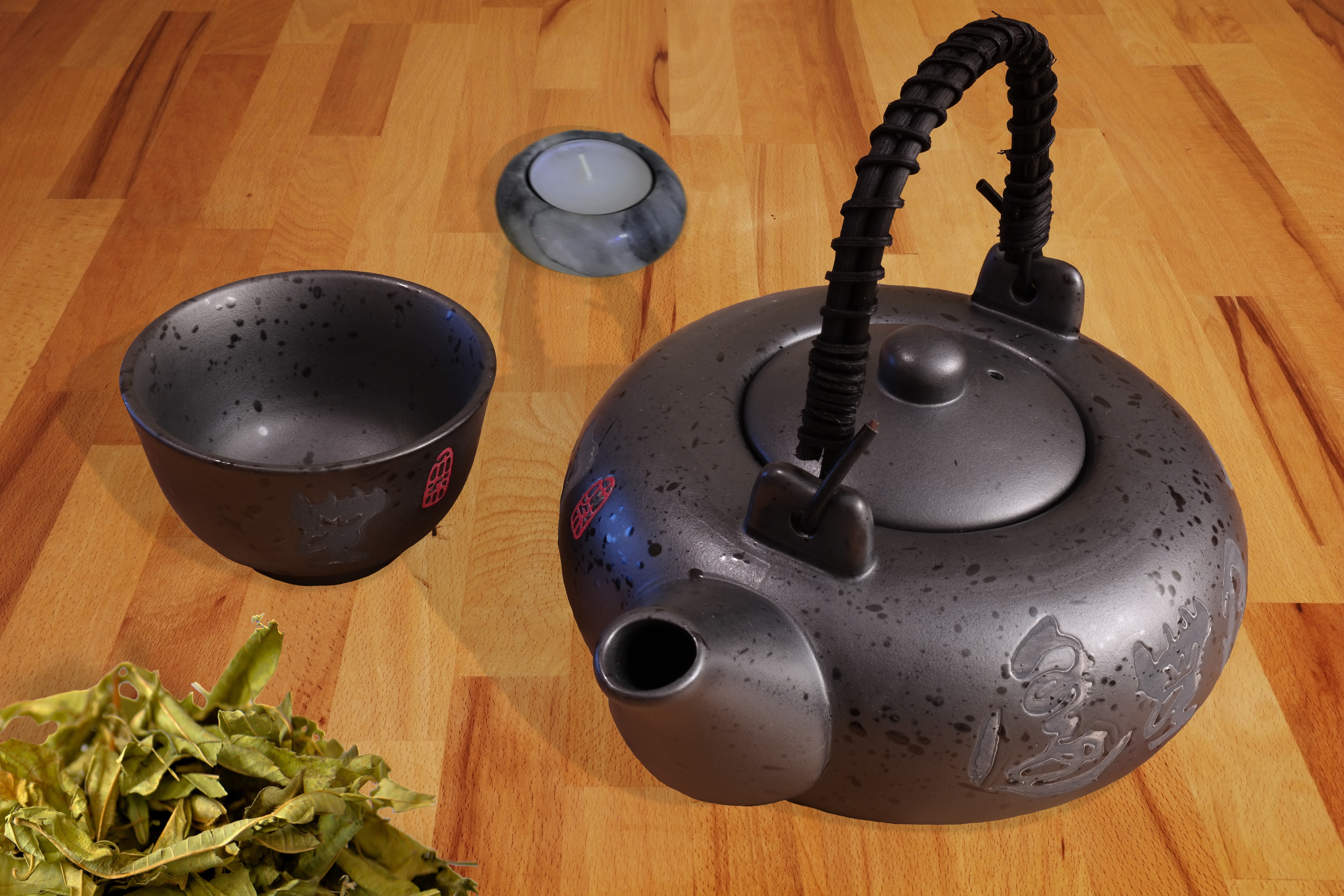 gray steel kettle beside gray steel cup on top of brown wooden surface