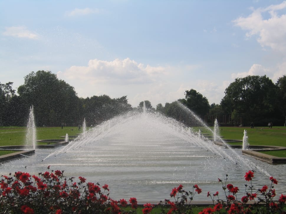 white outdoor fountain surrounded by green grass under clear sky during daytime preview