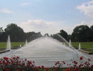 white outdoor fountain surrounded by green grass under clear sky during daytime thumbnail