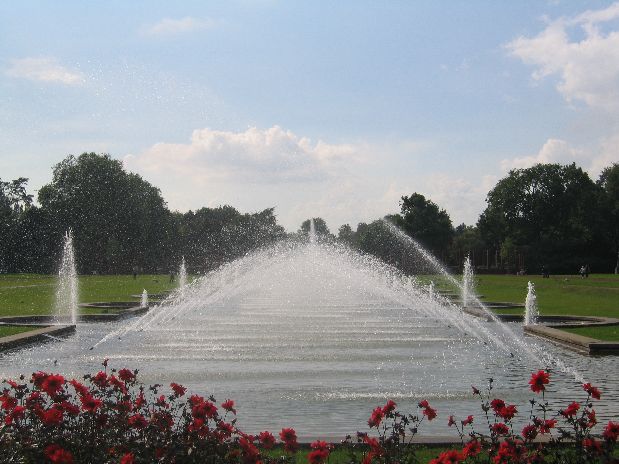 white outdoor fountain surrounded by green grass under clear sky during daytime